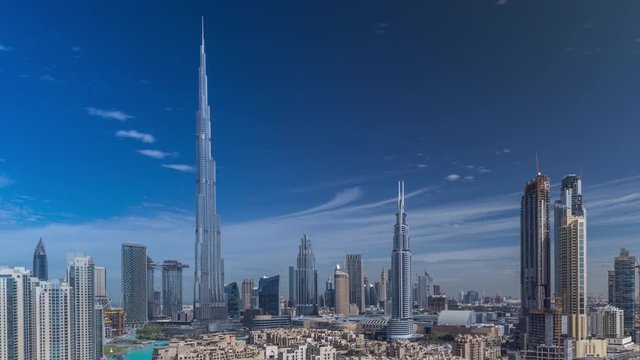 Dubai Downtown skyline timelapse with Burj Khalifa and other towers paniramic view from the top in Dubai, United Arab Emirates. Traffic on circle road and old style buildings