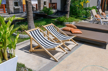 Wooden sunbeds with mattress on side of swimming pool