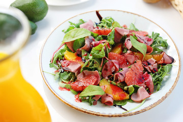 Healthy diet. Green lettuce with grapefruit, orange and ham served with balsamic vinegar sauce