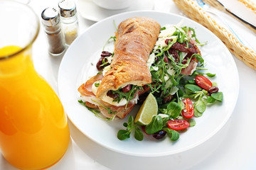 Sandwich with ham and vegetables. Roll sandwich served with ham and vegetables. appetizing nutritious breakfast.