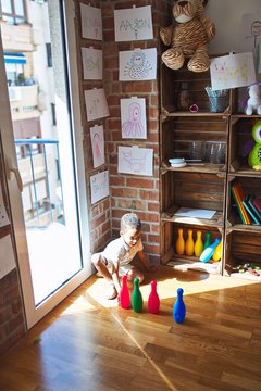 Beautiful african american toddler taking skittles to play bowling at kindergarten