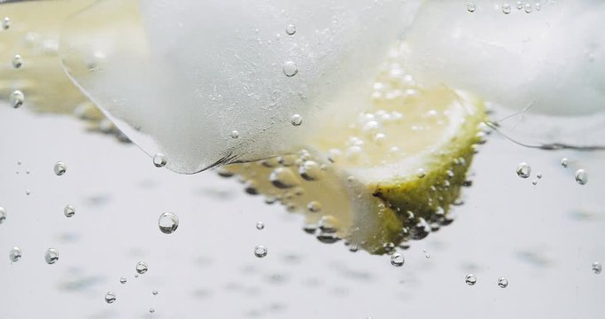 Lime ice and soda water bubbles turning close up