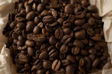Brown coffee beans in a parchment paper saucer. The view from the top. The concept of love for coffee.