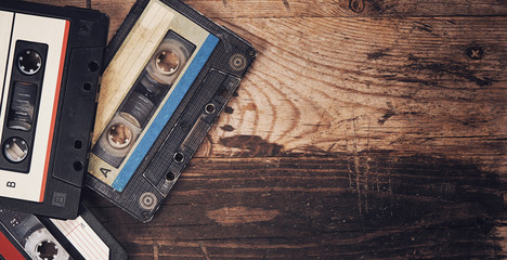 Old audio tape compact cassette on wooden background - obrazy, fototapety, plakaty