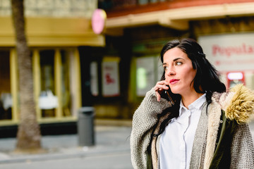 Middle-aged woman answering a call on her cell phone in the street.