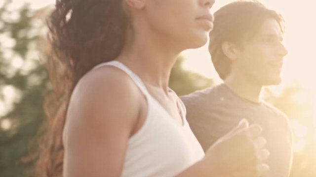 Cropped view of athletic couple man and woman in tracksuits running together while working out at playground outdoors