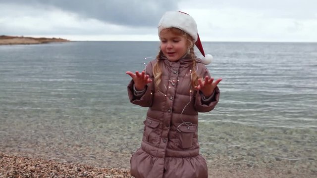 Little girl in santa hat tries make air kiss