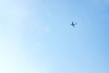 Plane flies high in blue sky from right to left
