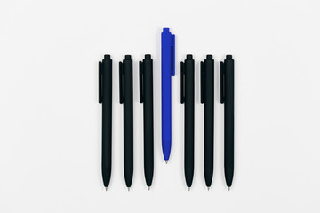 Blue pen and black pens. Concept of being different. Trendy color 2020. Flat lay style.