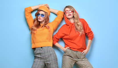 Fashionable woman in stylish outfit, makeup posing on blue. Two Beautiful blonde redhead tomboy...