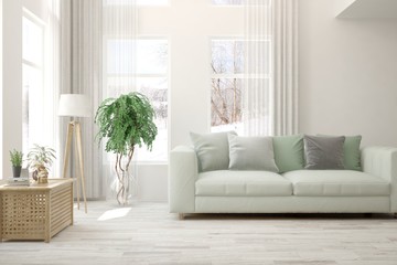 Fototapeta premium Stylish room in white color with sofa and winter landscape in window. Scandinavian interior design. 3D illustration