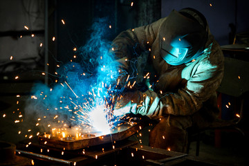 Welder works with a metal product. Beautiful sparks in the dark