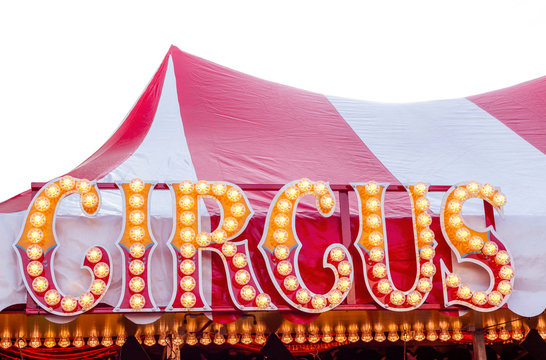 Circus sign with circus lettering against a red and white striped circus tent