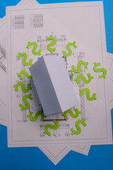 Paper skyscrapers , us dollar money, house projects plan and blueprints on blue background paper. Minimalistic and simple concept, style. Horizontal orientation. View from above. Copy space.