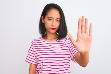 Young chinese woman wearing striped t-shirt standing over isolated white background doing stop sing...