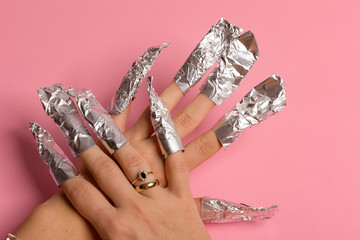 The procedure for removing varnish from nails hybrid nails in progress. Gel nail polish remover foils on woman's hands.