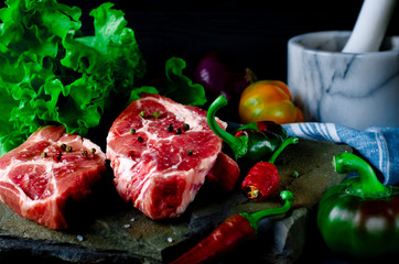 A set of raw products for the preparation of juicy meat steak with vegetables against a background of wild multicolored stone