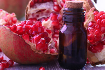 Pomegranate seed oil in bottle and pomegranate on wooden background