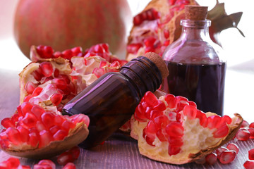 Pomegranate seed oil in bottle and pomegranate on wooden background