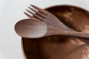 recycling, tableware and eco friendly concept - close up of coconut bowl with brown wooden spoon...