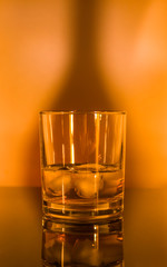 Glass whisky glass with ice in orange light