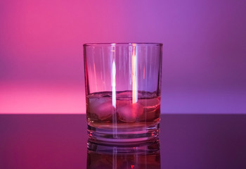 Glass whiskey glass with ice in neon light