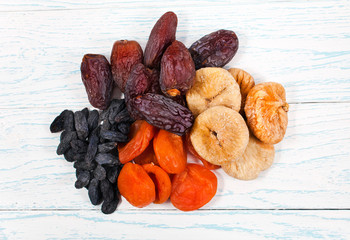 Heap of dried fruits (fig, apricot, dates, raisins) on old wooden background. Top view. 