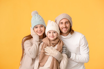 Happy family in winter clothes on color background