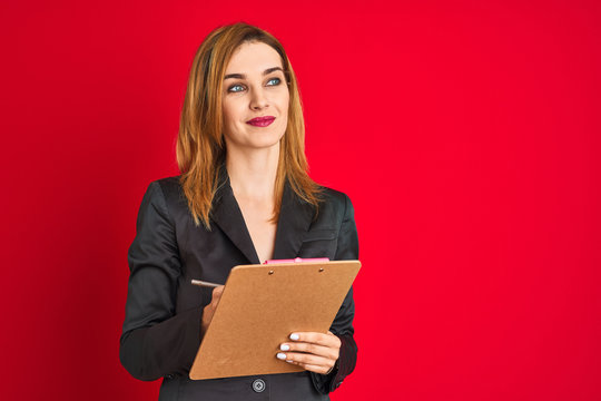 Young beautiful redhead businesswoman wearing suit writing on flip board