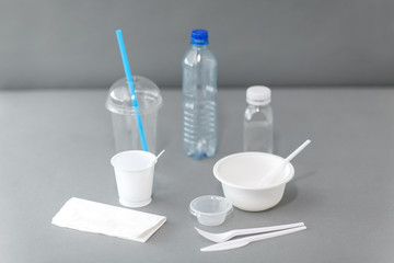 eating, recycling and ecology concept - disposable plastic dishes on grey background