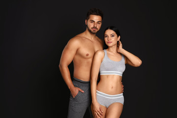 Young couple in grey sportive underwear on black background
