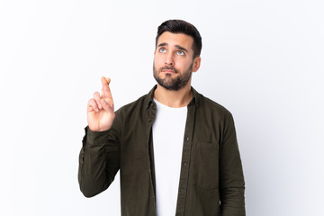 Young handsome man with beard over isolated white background with fingers crossing and wishing the best