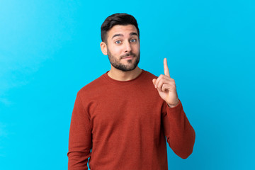 Young handsome man with beard over isolated blue background pointing with the index finger a great idea