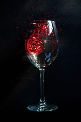 concept spilled red wine. end of the party. a glass of wine lying on a table in it red stars symbolizing spilled wine