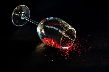 concept spilled red wine. end of the party. a glass of wine lying on a table in it red stars symbolizing spilled wine