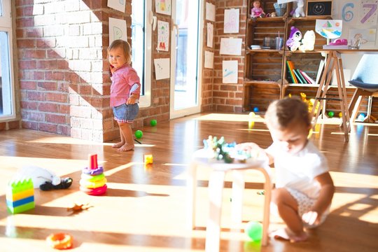 Adorable toddlers playing around lots of toys at kindergarten