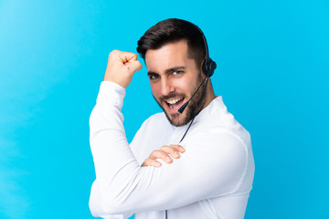 Naklejka premium Telemarketer man working with a headset over isolated blue background making strong gesture