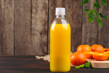 Bottle of orange juice with oranges on wooden table