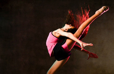 Young slim athletic girl gymnast dancer jumping up stretching doing gymnastic exercises in studio...