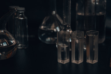 Set with different laboratory glassware and liquid for analysis on black background Glass chemistry...