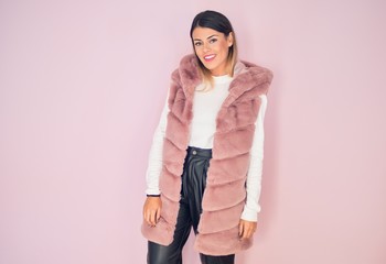 Young beautiful woman wearing fashionable clothes smiling happy and confident. Standing with smile on face over isolated pink background