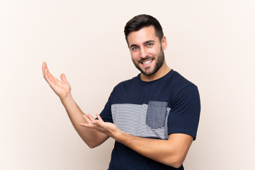 Young handsome man with beard over isolated background extending hands to the side for inviting to come