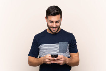 Young handsome man with beard over isolated background sending a message with the mobile