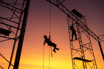 Male working abseiling on a construction site silhouette worker - Powered by Adobe