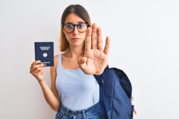 Beautiful redhead student woman wearing backpack and holding passport of germany with open hand doing stop sign with serious and confident expression, defense gesture