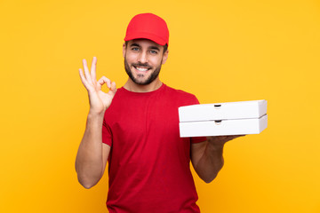 pizza delivery man with work uniform picking up pizza boxes over isolated yellow background showing...