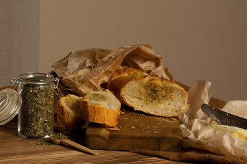 Sliced baguette, butter and herbs spices on a wooden board