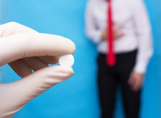 Obraz premium The doctor holds a pill in his hand against the background of a man who has pain and inflammation in his stomach. Concept cure for gastritis and stomach ulcers.
