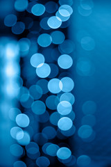 Glitter bokeh of night lights of classic blue garlands of 2020. Vertical background for creativity and design.