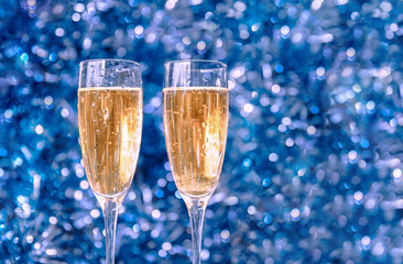 Two beautiful Christmas glasses with splashes and Christmas decorations with bokeh in the foreground, mysterious new year background.